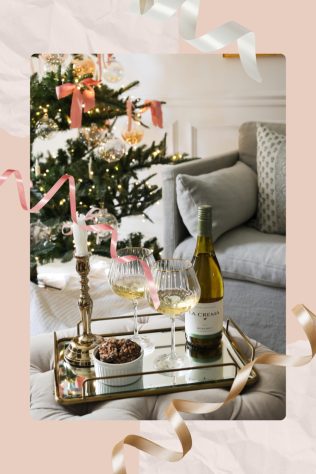 Bottle of La Crema wine with two wine glasses on a tray in front of a holiday tree